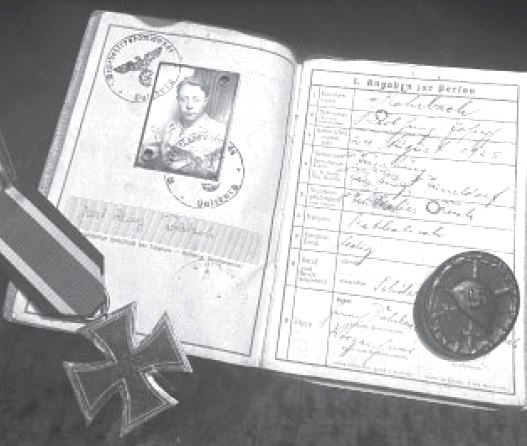 I documenti di Karl-Heinz Rohrbach: il libretto militare aperto, con la sua fotografia e i timbri, accanto a una croce di ferro con il nastro e a un distintivo rotondo.