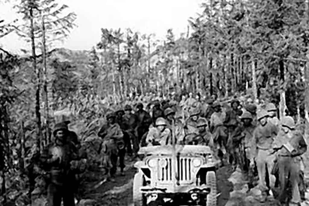 Gruppo di soldati in uniforme militare con jeep in un bosco, scena storica della Seconda Guerra Mondiale.