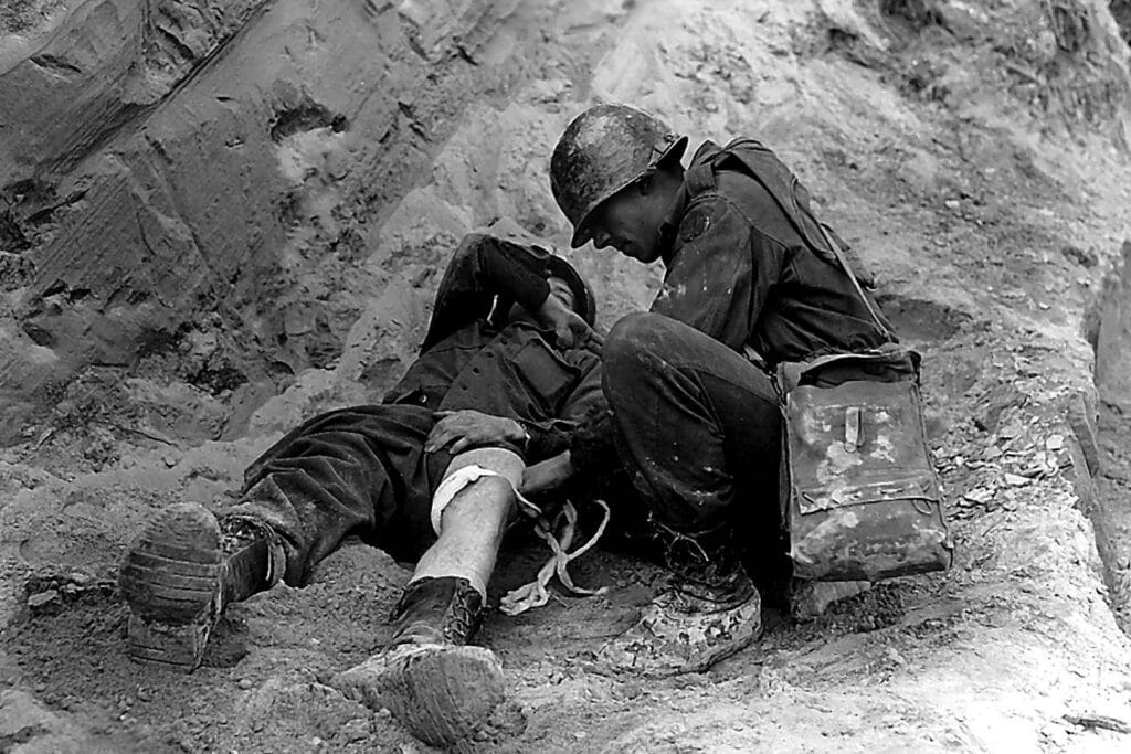 Soldato in uniforme militare aiuta un compagno ferito durante un'operazione di guerra in un ambiente di battaglia.