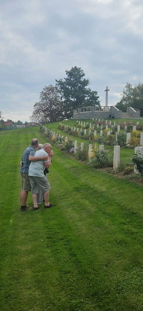 Un uomo anziano e il figlio si abbracciano fra le lapidi del cimitero di guerra sudafricano di Castiglione dei Pepoli