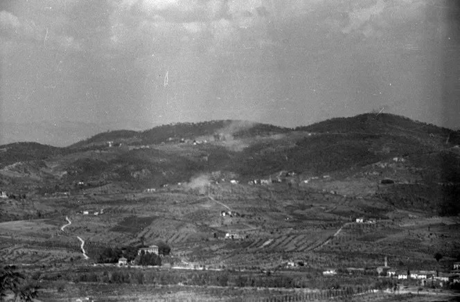 Nuvole di fumo di esplosioni sopra le case di San Michele, sulla cresta di una collina.