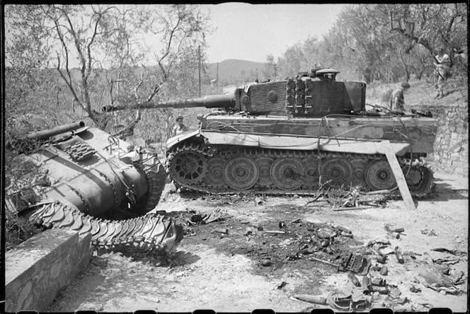 Un carro armato tedesco Tiger distrutto e uno Sherman rovesciato su una strada fra gli ulivi, a sud di Firenze, con alcuni soldati sullo sfondo.
